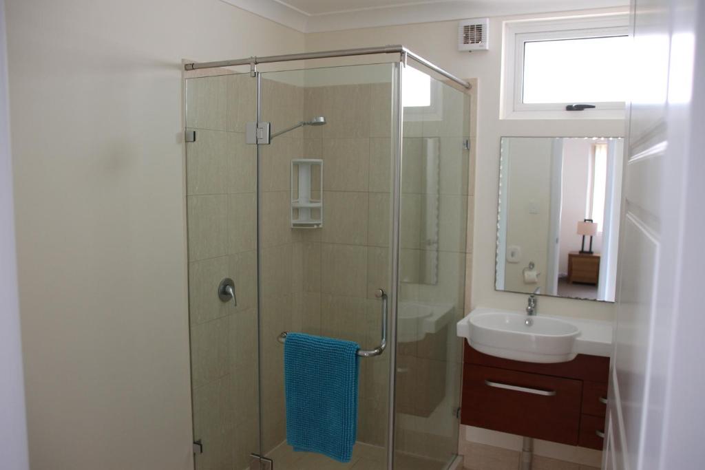 a bathroom with a glass shower and a sink at Seaspray Beach Holiday Park in Dongara