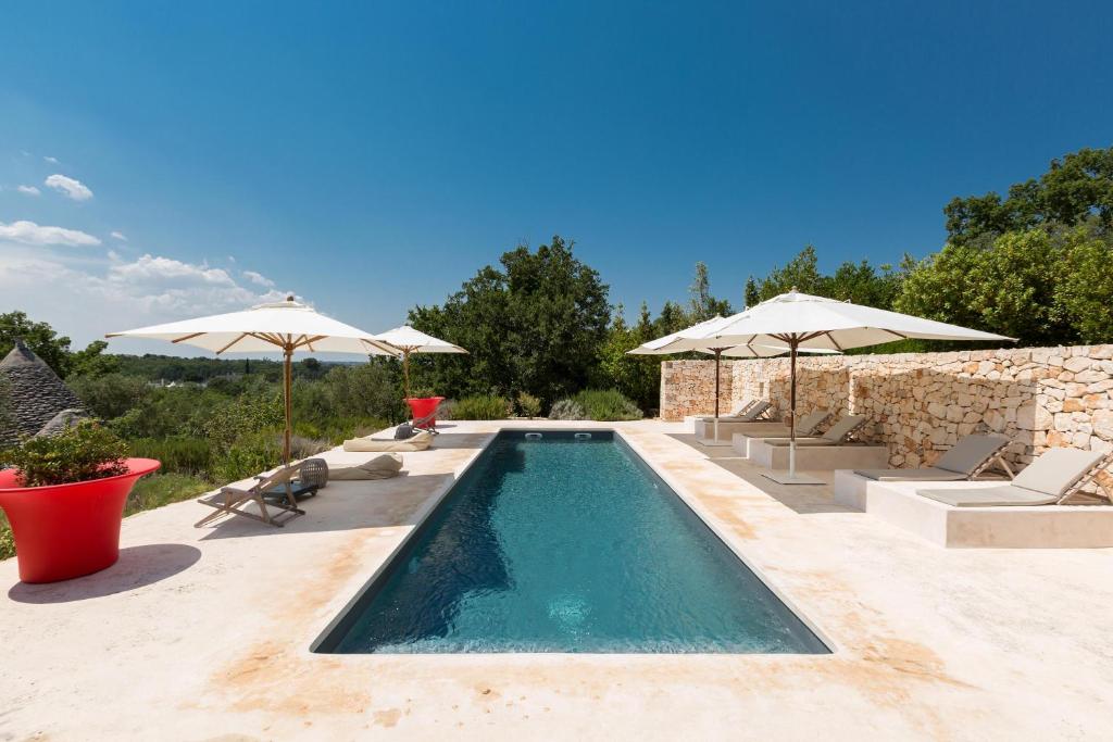 une piscine avec parasols et chaises et une piscine dans l'établissement La Gastalena by BarbarHouse, à Ostuni