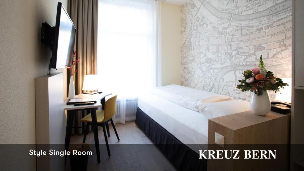 a hotel room with a bed and a desk and a window at Kreuz Bern Modern City Hotel in Bern
