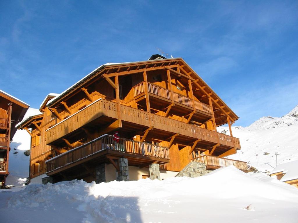 a large wooden building in the snow with snow at Bouquetin Appartements VTI in Val Thorens