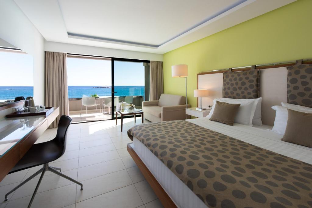 a hotel room with a bed and a desk with a view at Alimounda Mare Hotel in Karpathos