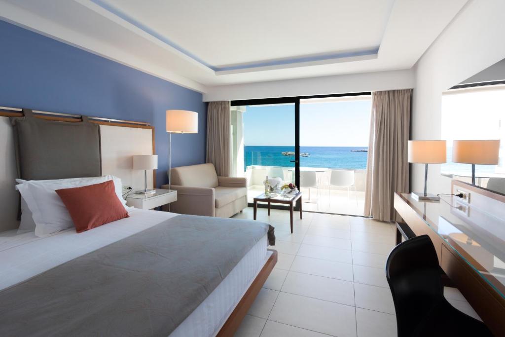 a hotel room with a bed and a view of the ocean at Alimounda Mare Hotel in Karpathos