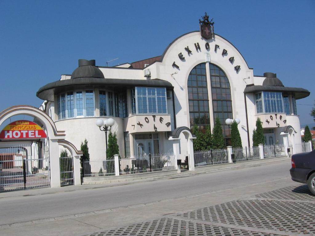 a white building with a clock on top of it at Hotel Tehnograd in Kraljevo