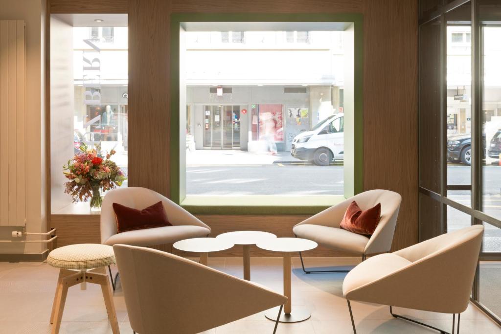 a lobby with chairs and a table and a window at Kreuz Bern Modern City Hotel in Bern