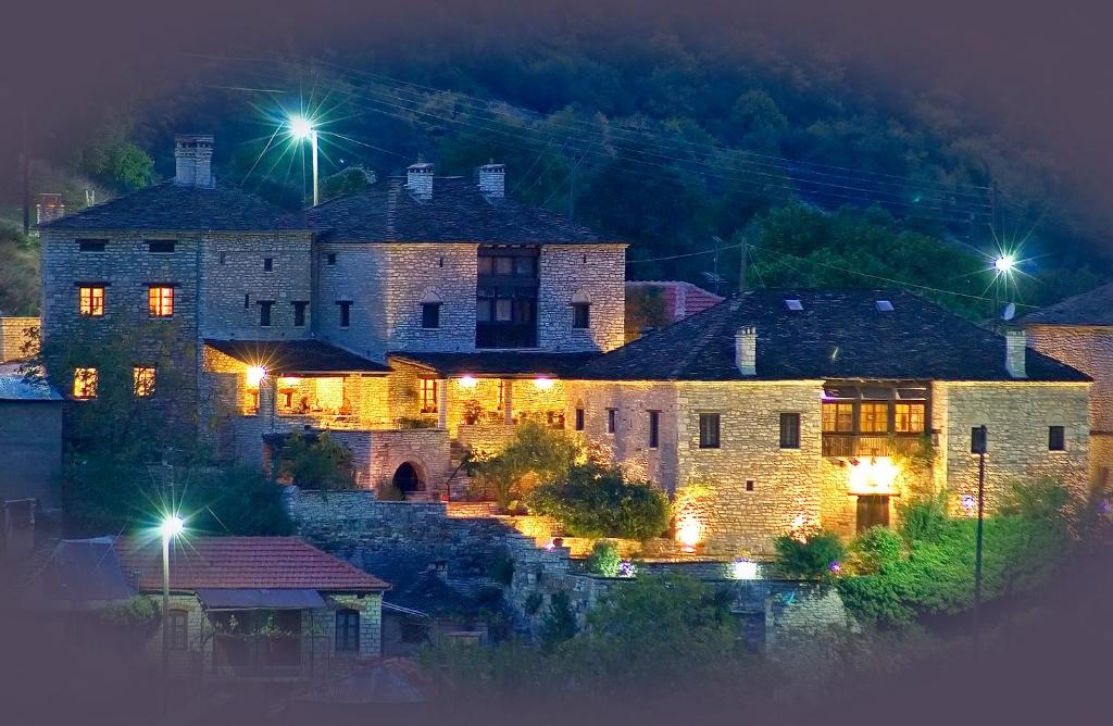 Un grand bâtiment en pierre avec des lumières allumées la nuit dans l'établissement Arhontiko Aristis, à Aristi