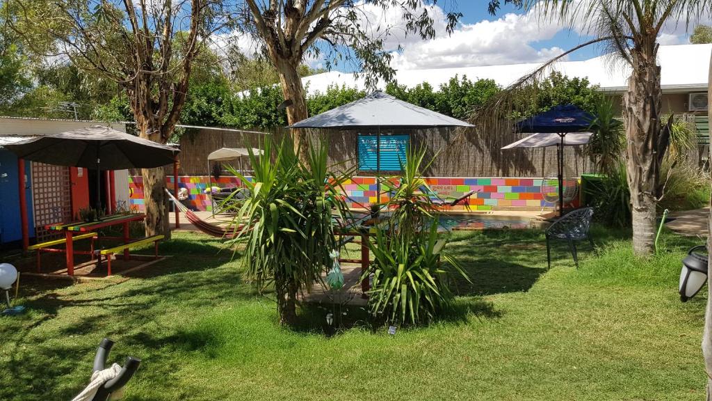 a yard with a playground with a table and an umbrella at Alice's Secret Travellers Inn in Alice Springs