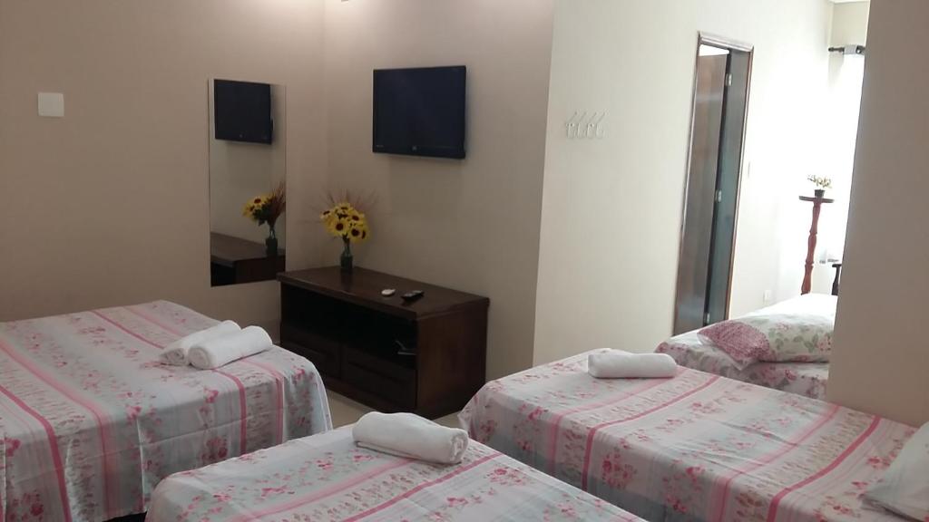 a room with two twin beds and a mirror at Pousada Alelo in Guarujá