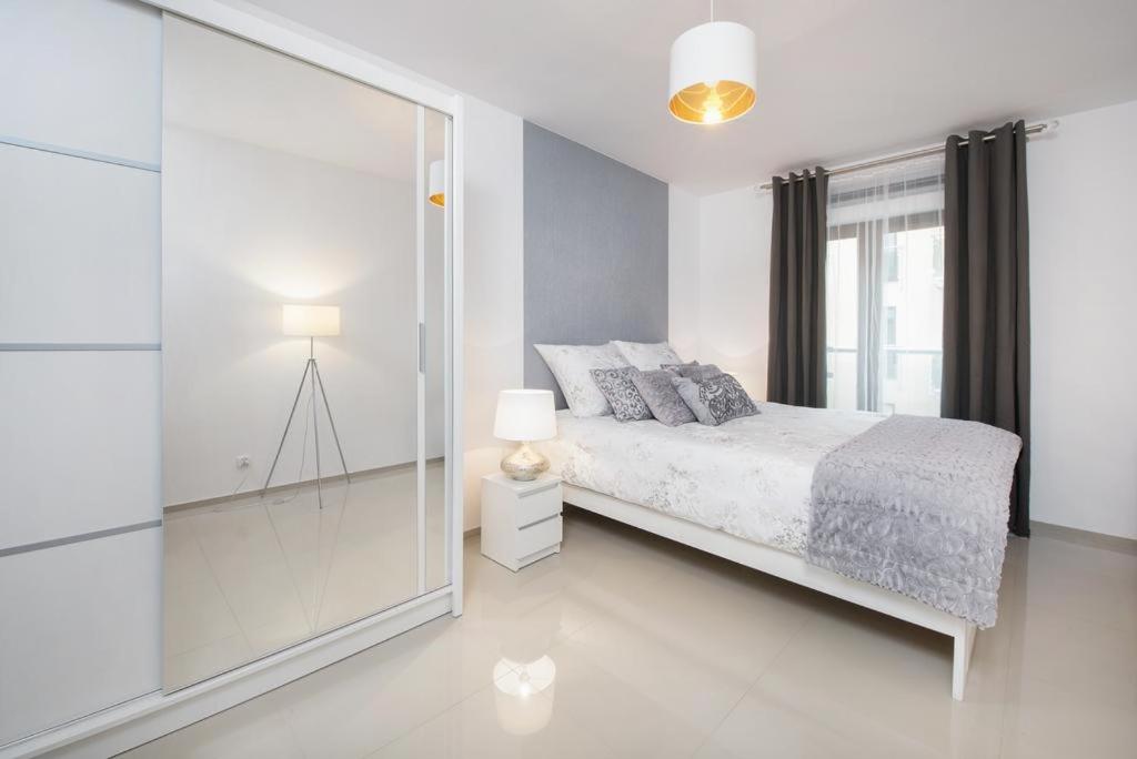 una camera bianca con un letto e una parete di vetro di Icon Apartments Centrum 55m2 a Breslavia