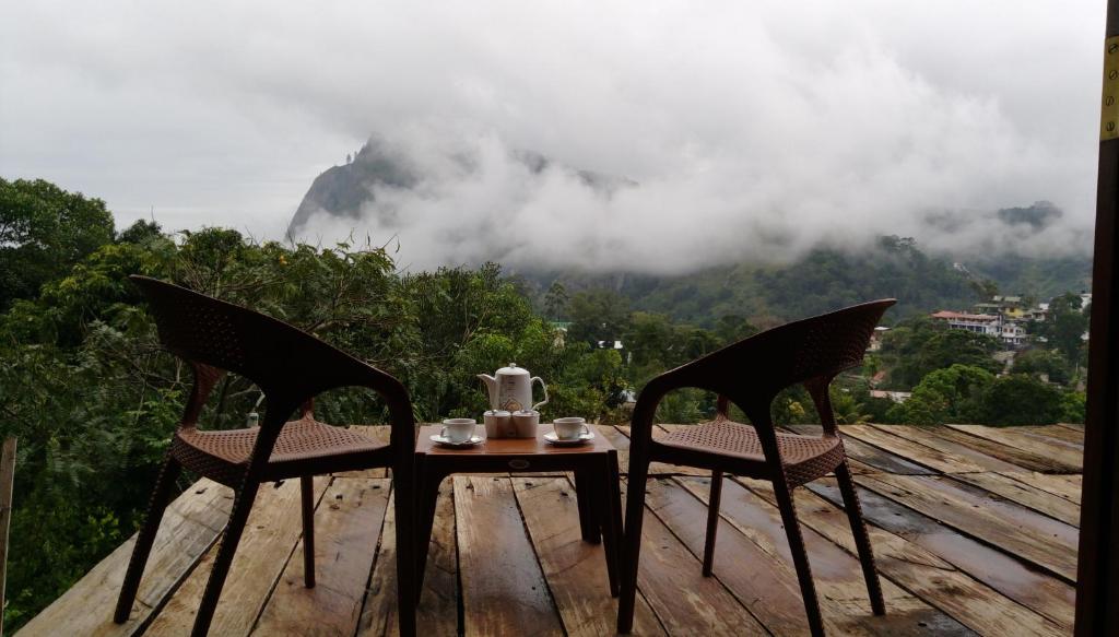 a table and chairs on a deck with a view of a mountain at Ella Rawana Den Hotel in Ella