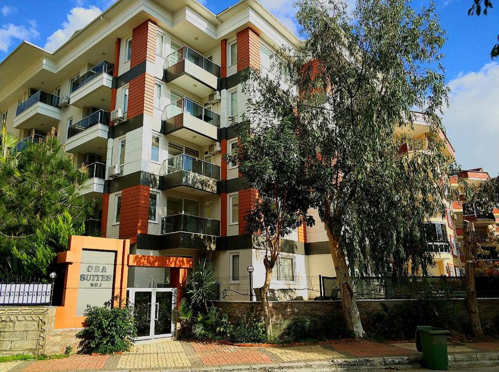 a large apartment building with a tree in front of it at Oba Suites Apartmani in Alanya