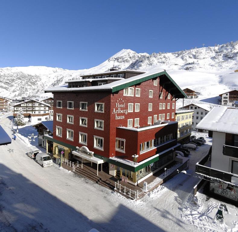 Außenansicht des Hotel Arlberghaus in Zürs mit traditioneller alpiner Architektur im Winter, schneebedecktes Dach und Balkone