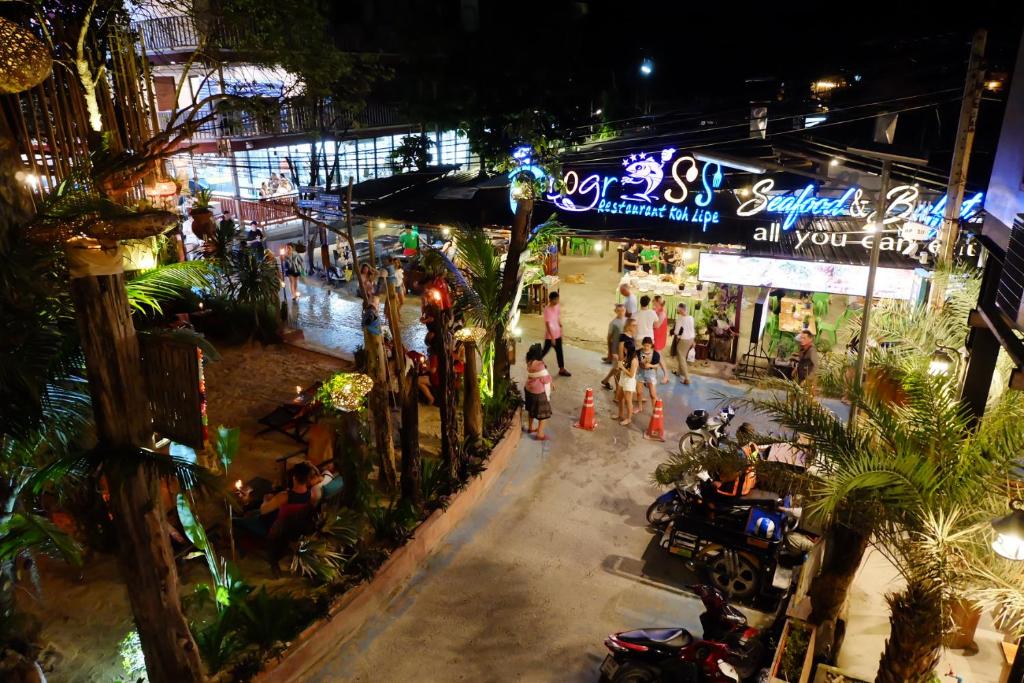 a group of people walking down a street at night at Bloom Cafe & Hostel in Ko Lipe
