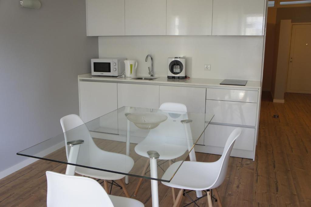 a glass table and white chairs in a kitchen at Apartamento Copacabana in Estoril