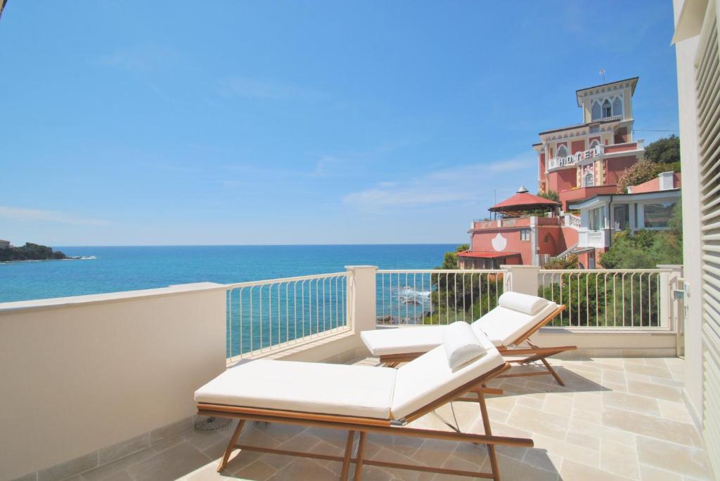 een balkon met twee witte stoelen en de oceaan bij Il Quercetano in Castiglioncello