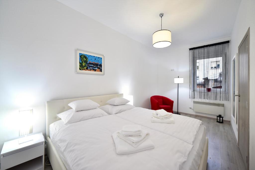 um quarto branco com uma cama branca e uma cadeira vermelha em Apartment Sermazi em Zagreb