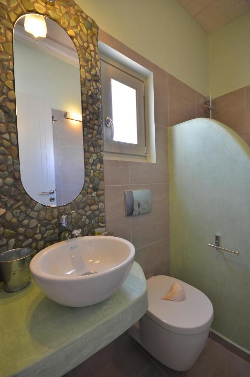 a bathroom with a sink and a toilet and a mirror at Portes Houses in Koufonisia