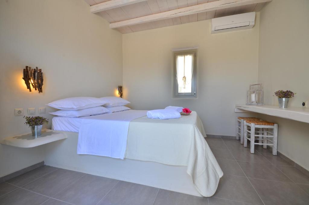 a white bedroom with a bed with white sheets and pillows at Portes Houses in Koufonisia