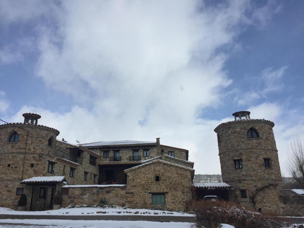 Matute de la Sierra的住宿－Casona Santa Coloma，一座古老的石头建筑,在雪中有两个塔