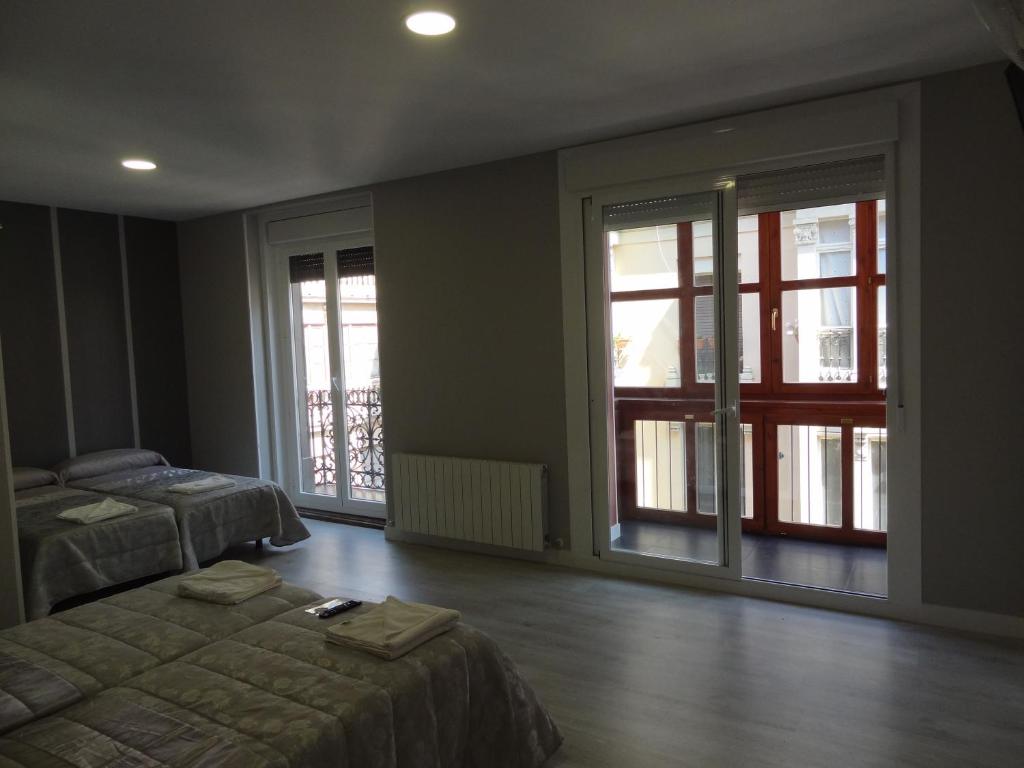 a bedroom with two beds and sliding glass doors at Pensión La Bilbaina - Albergue Logroño in Logroño