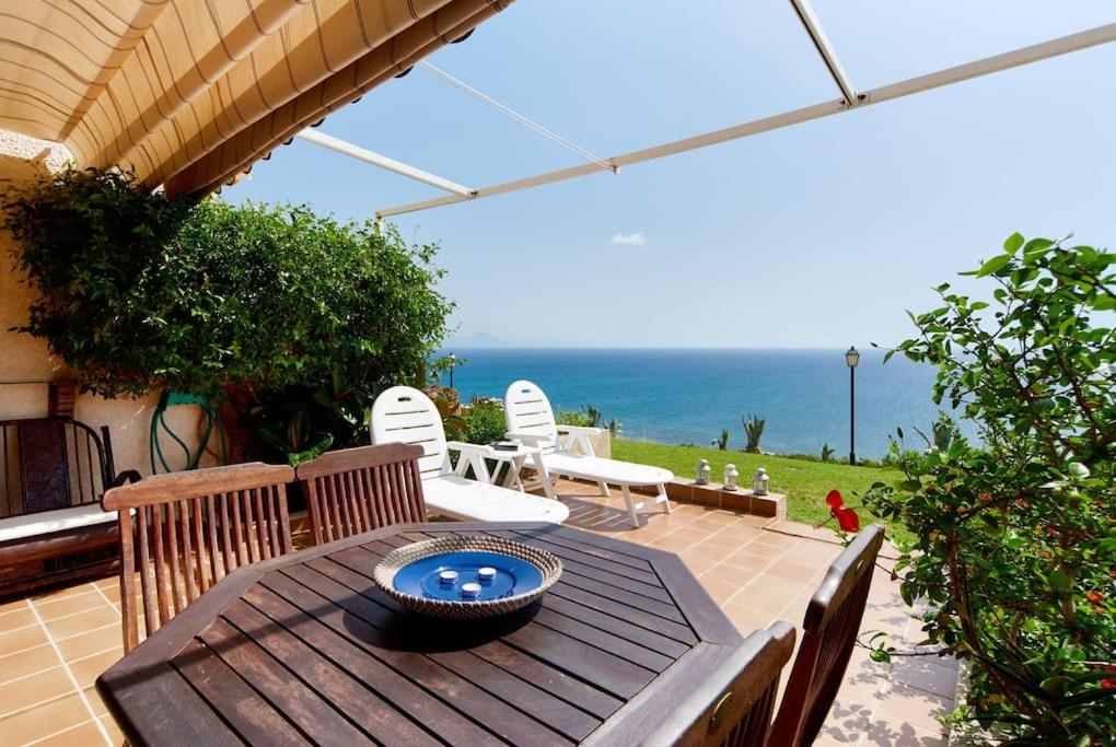 een houten tafel en stoelen op een patio met uitzicht op de oceaan bij VISTAS INFINITAS SOBRE EL MAR-INFINITE VIEWS On THE SEA in Santa Pola