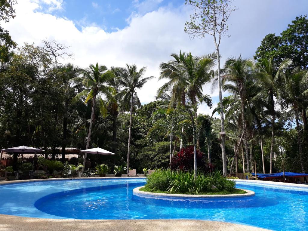 uma piscina num resort com palmeiras ao fundo em Calape Forest Resort em Calape