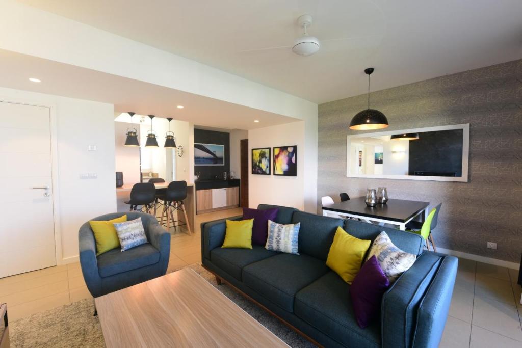 a living room with a blue couch and yellow pillows at Luxury Apartment - Azuri Village - Roches Noires in Roches Noires