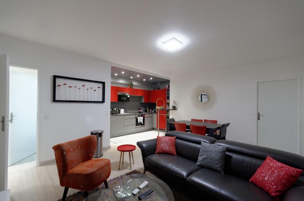 ein Wohnzimmer mit einem schwarzen Ledersofa und einer Küche in der Unterkunft Red-line in Serris