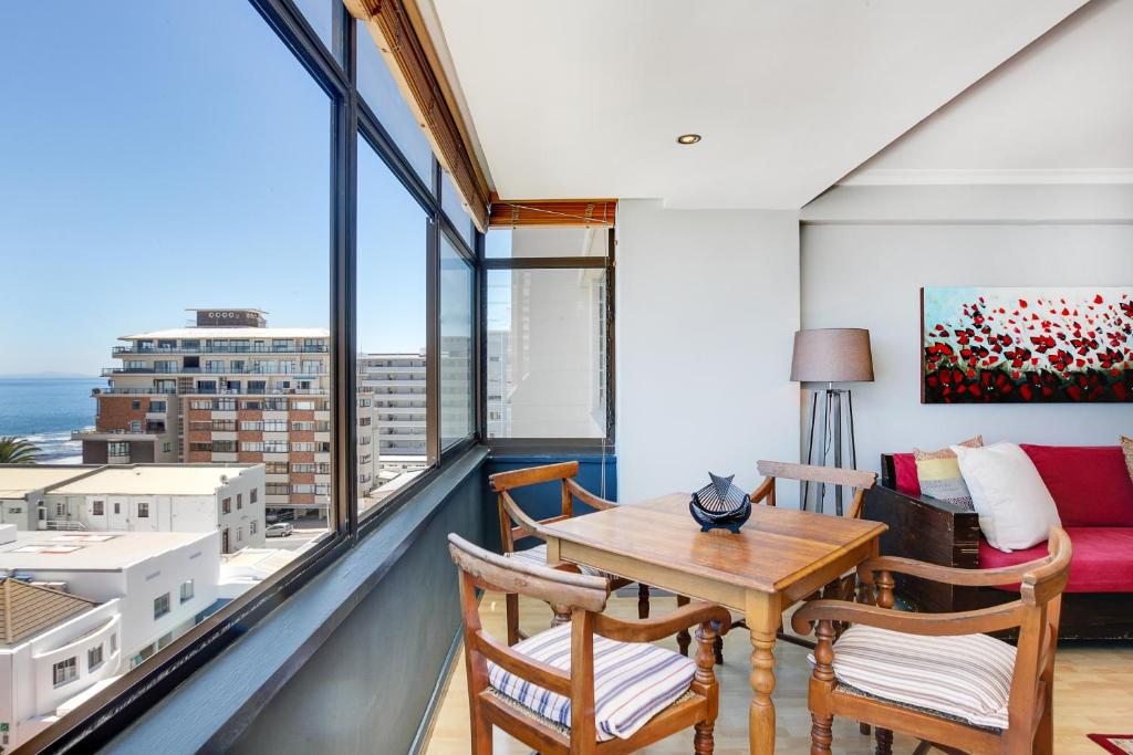 balcón con mesa, sillas y sofá en Backup-Powered Bantry Bay View 2 Bed Apartment, en Ciudad del Cabo