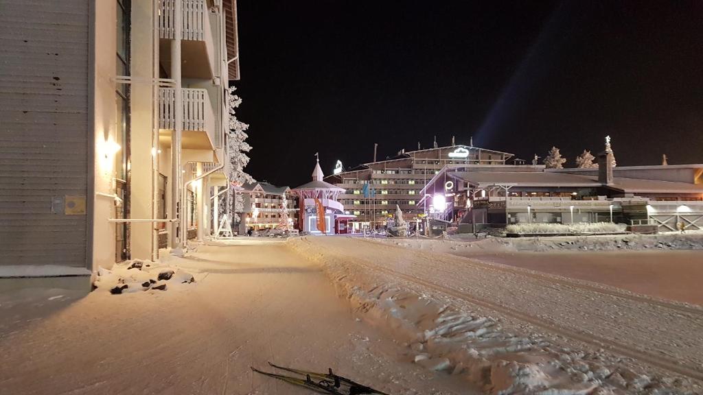 een besneeuwde straat 's nachts met gebouwen en verlichting bij Ruka Chalets Ski-Inn in Ruka