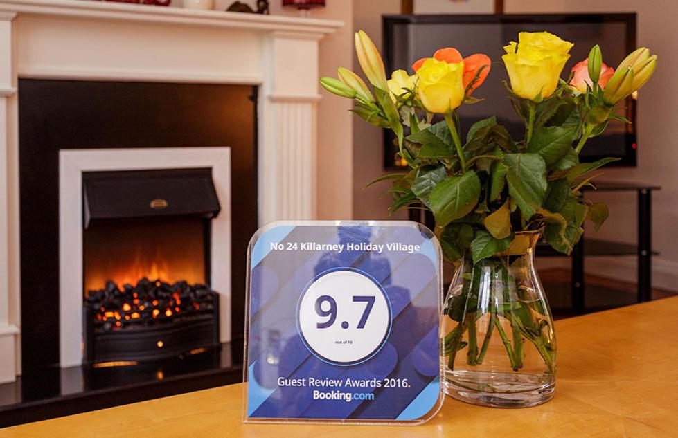 a vase with flowers and a clock on a table with a fireplace at Kerry Holiday Homes at the Killarney Holiday Village in Killarney