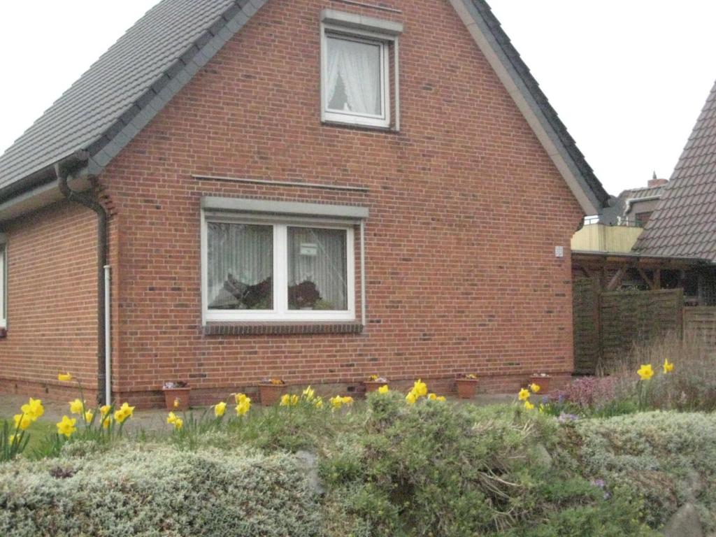 una casa de ladrillo rojo con flores amarillas delante de ella en Haus Peters, en Büsum