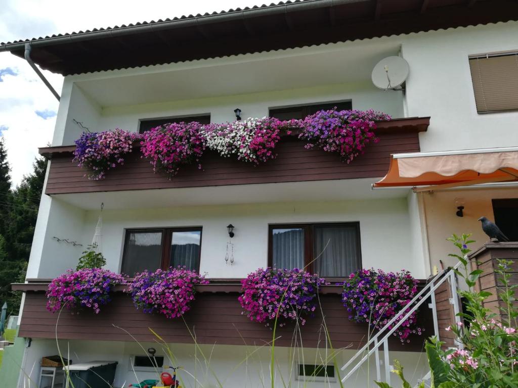ein Haus mit lila Blumen auf dem Balkon in der Unterkunft Ferienwohnung Resi mit traumhaftem Seepanorama in Steindorf am Ossiacher See