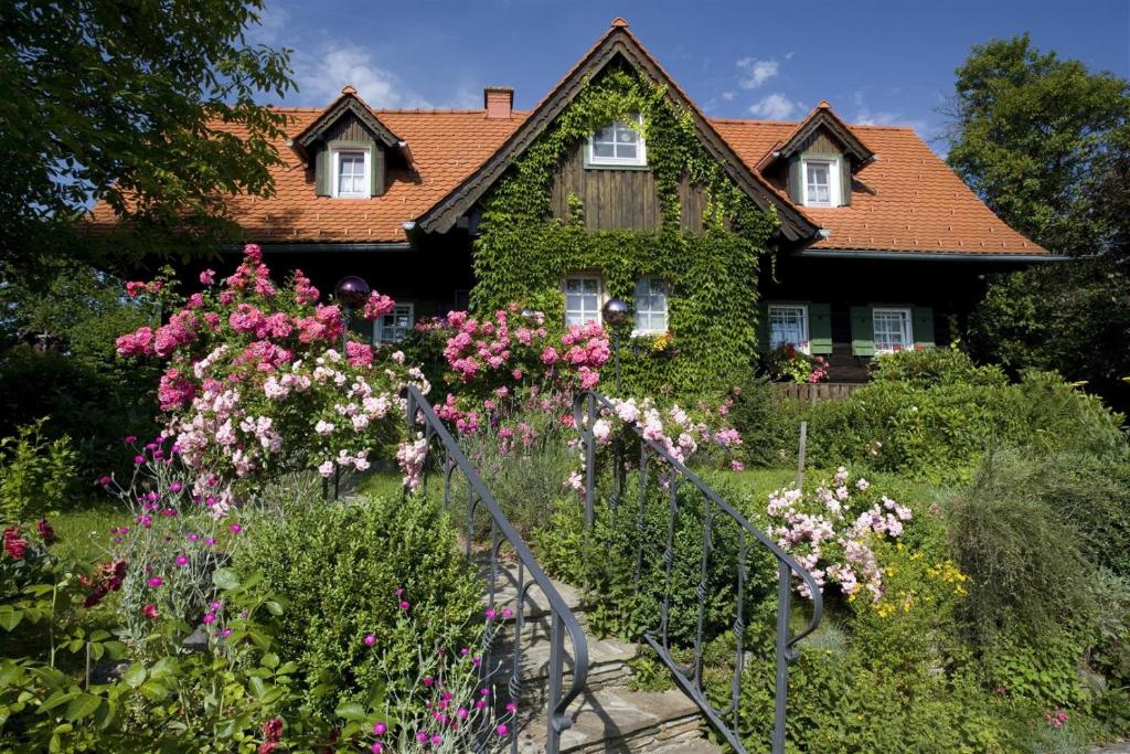une maison avec un jardin de fleurs devant elle dans l'établissement Altes Gehöft am Lormanberg, à Kirchberg an der Raab