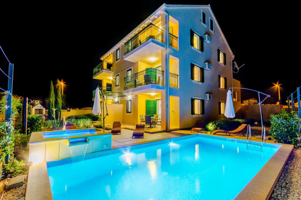 a house with a swimming pool in front of a building at Vila Mimoza in Milna