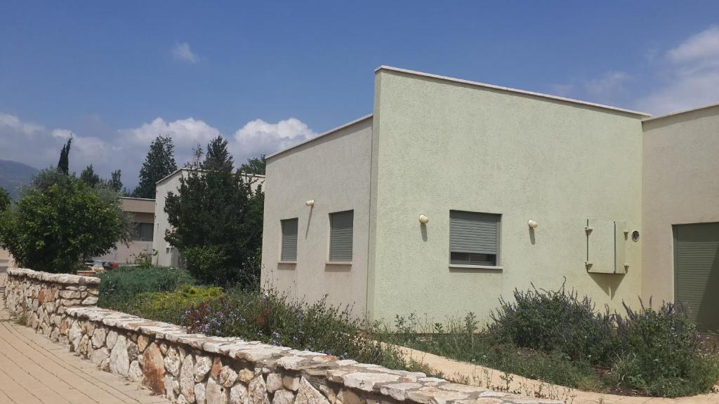 a building with a stone wall next to a street at Holiday home in Galilee in Sheʼar Yashuv