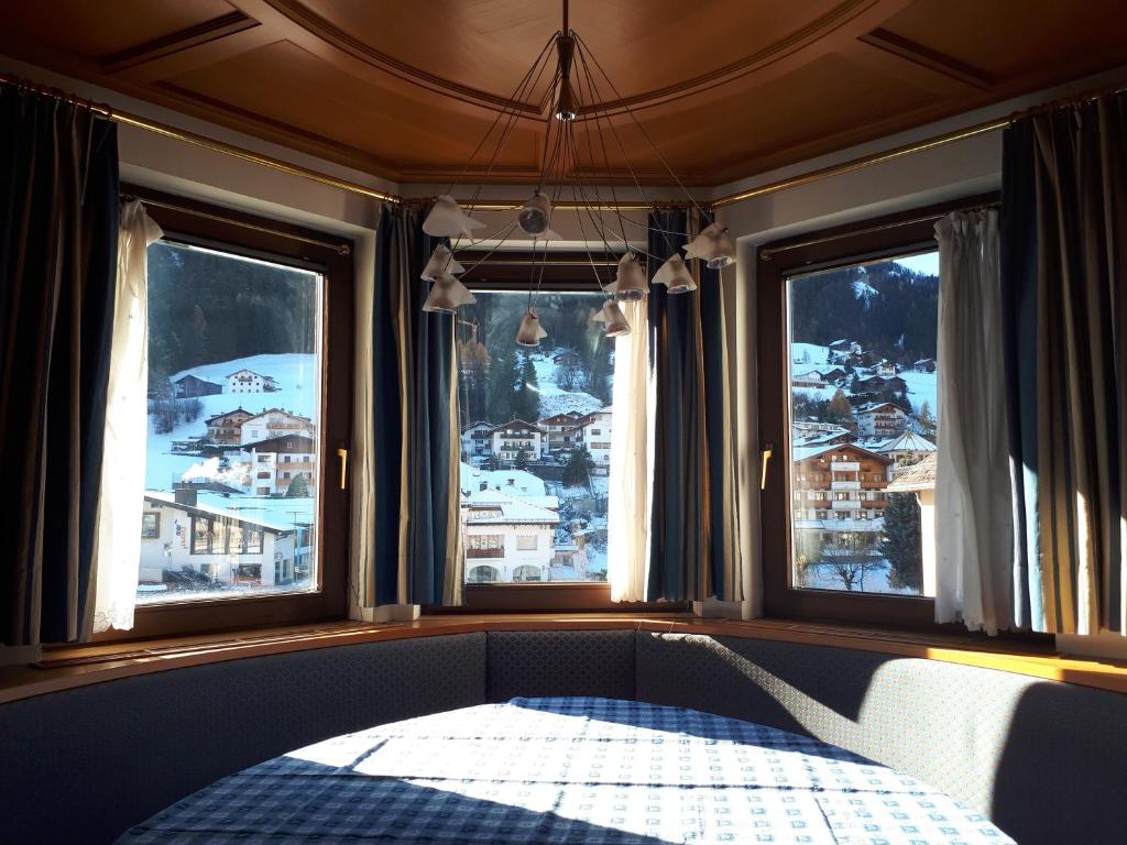 een bed in een kamer met 3 ramen met sneeuw bij Dreaming Ortisei in Ortisei