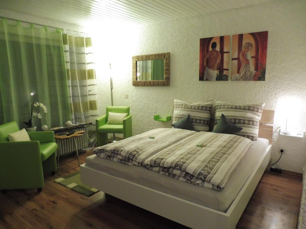 a bedroom with a bed and two green chairs at Grün und herzlich in Oberstaufen