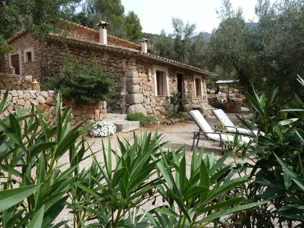 a stone house with two lounge chairs in front of it at Casita de Montaña cerca del mar in Fornalutx