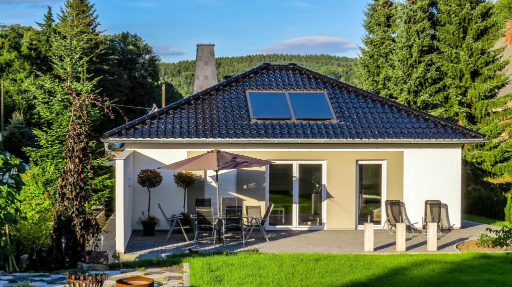 Casa blanca pequeña con sillas y sombrilla en Ferienhaus im Erzgebirge, en Chemnitz