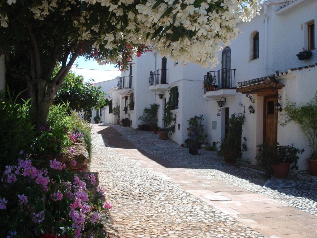 a street with white buildings and flowers on the side at El Capistrano Sur in Nerja