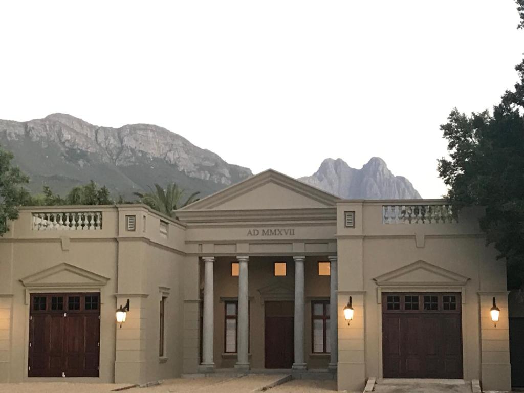 a large white building with mountains in the background at At Home in Mostertsdrift in Stellenbosch