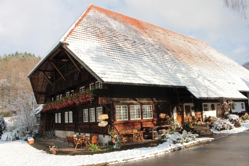 ein großes Holzhaus mit Schnee auf dem Dach in der Unterkunft Rommelehof in Gutach