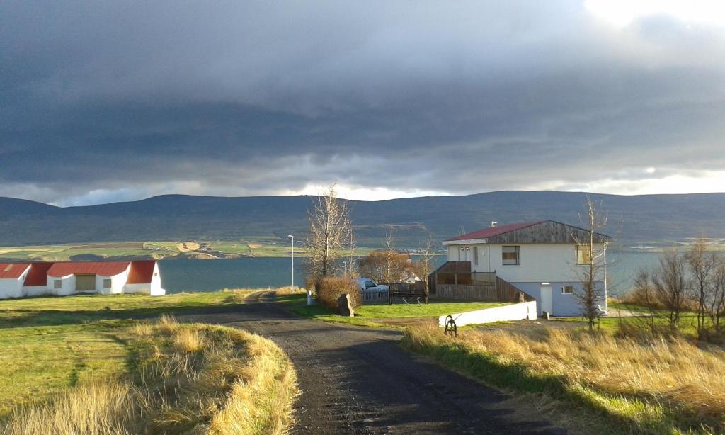 eine unbefestigte Straße mit einem Haus an der Seite eines Feldes in der Unterkunft Glæsibær 2 Guesthouse and horsefarm in Akureyri