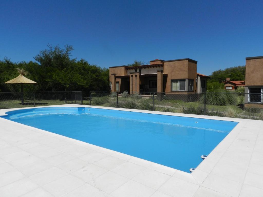 a large blue swimming pool in front of a house at Verbenas de las Sierras in Cortaderas