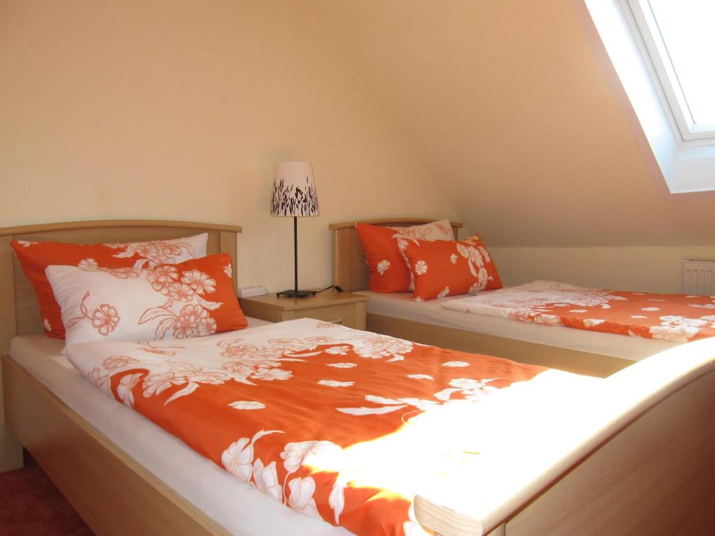 a bedroom with two beds with orange sheets and a window at Pension Roez in Göhren-Lebbin