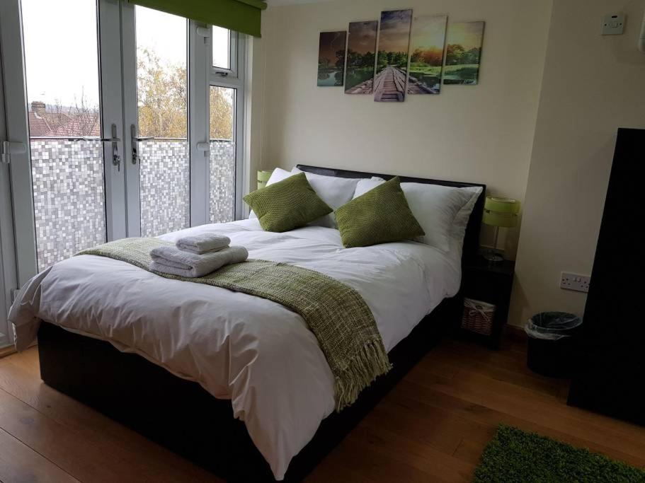 a bedroom with a large bed with green pillows at Modern ★★★★★ Top Floor Studio Apartment Getaway in London