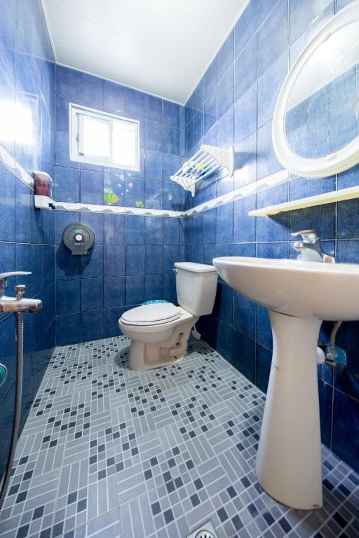 a blue tiled bathroom with a toilet and a sink at Blue Sea Romance B&amp;B in Green Island