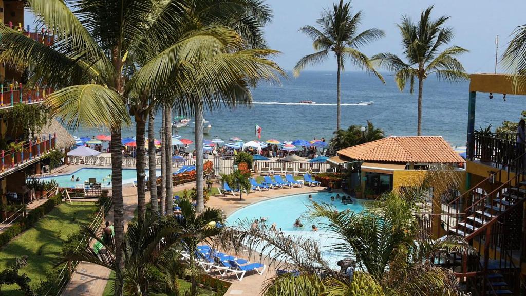 a view of a resort with a swimming pool and the ocean at Cabañas del Capitan in Rincon de Guayabitos