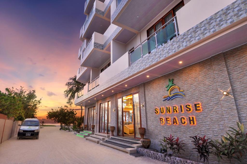 ein Gebäude mit einem Schild, das den Sonnenaufgang am Strand liest in der Unterkunft Sunrise Beach in Maafushi