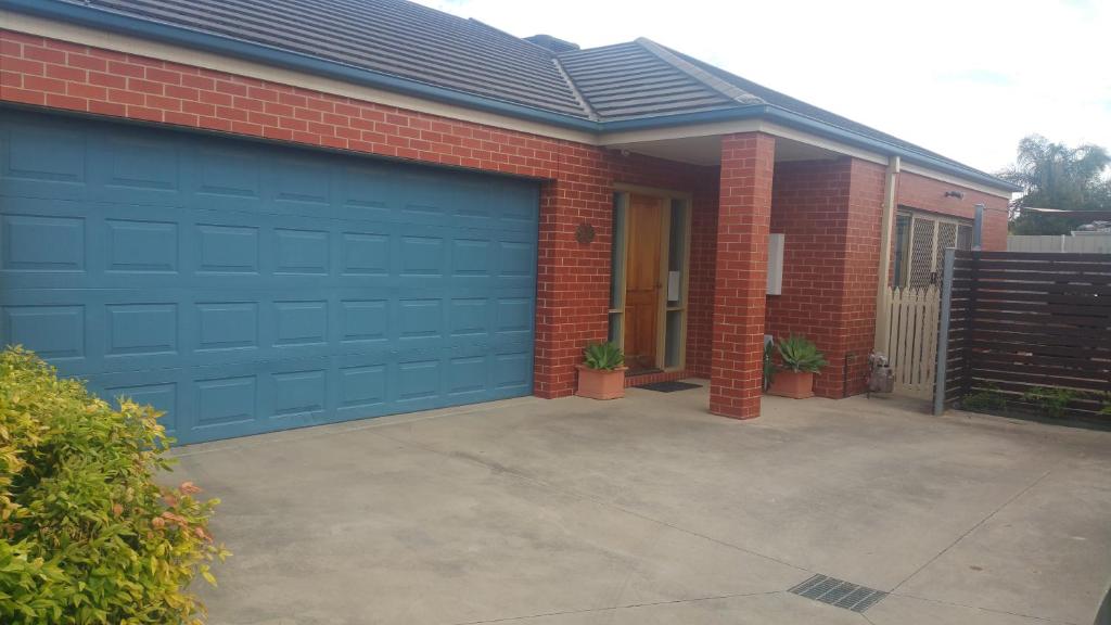 una porta blu del garage su una casa di mattoni di Annesley Central a Echuca